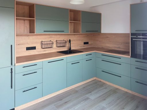 Moderne Einbauküche in Salbeigrün mit Holznischenrückwand, schwarzer Armatur und Griffen, ergänzt durch offene Fächer.